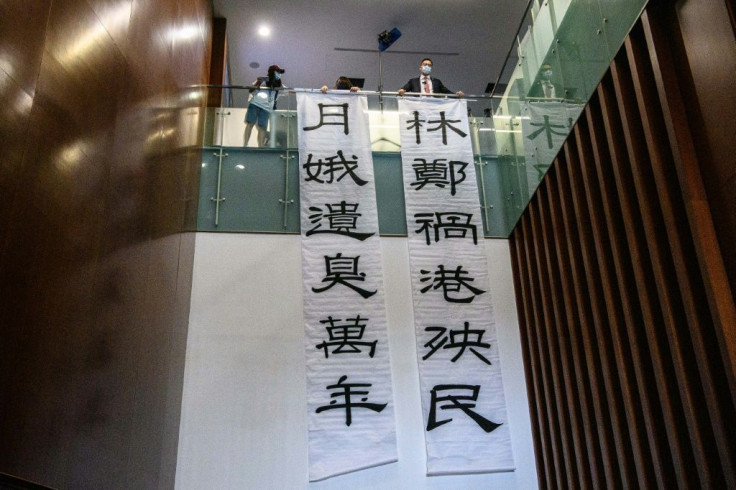 Banners reading 'Carrie Lam, the scourge of Hong Kong and its people' (R) and 'Carrie Lam, leaves a stink for ten thousand years' (L) are displayed by pro-democracy lawmaker Lam Cheuk-ting (top R) outside the main chamber of the Legislative Council