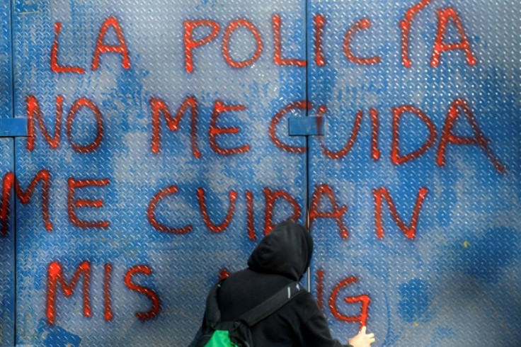 A woman writes "Police don't take care of me" on a wall during a demonstration in the Mexican capital