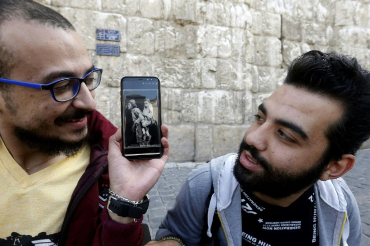 Bader al-Hajjami holds up a black and white photograph that shows two men who also reportedly lived in Damascus - one who was blind and carrying his friend, who could see but not walk