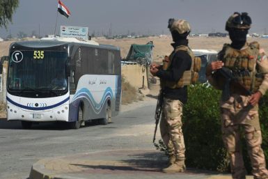 Iraqi soldiers secure buses transporting displaced families out of the shuttered camp in Habbaniyah in Iraq's Anbar province