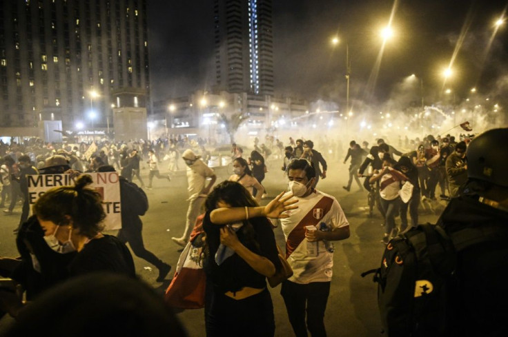 Demonstrators run away from tear gas during a protest in Lima