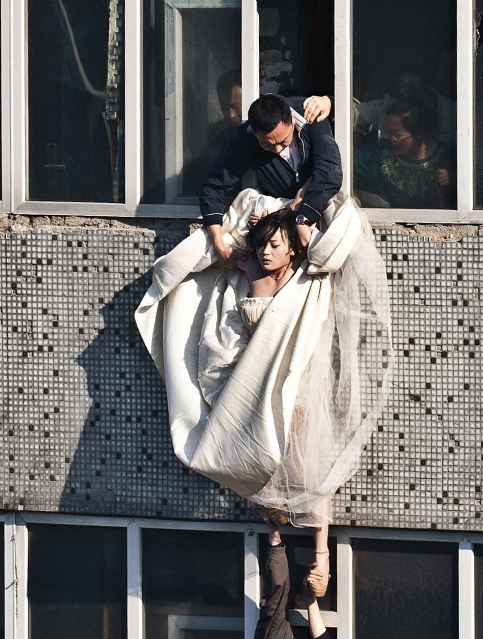Woman in wedding gown is grabbed by local community officer, as she attempts to kill herself by jumping out of seven-storey residential building in Changchun