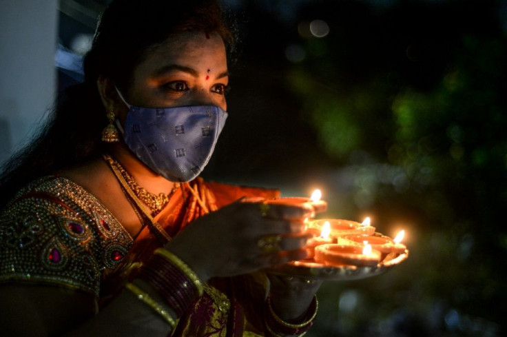 A Hindu devotee wears a mask as she places earthen lamps or 'diyas' at her home on the eve of Diwali