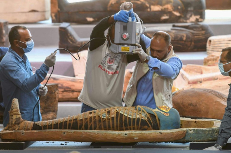 Archaeologists x-ray a mummy wrapped in a burial shroud and adorned with brightly coloured hieroglyphic pictorials, during the unveiling more than a 100 intact sarcophagi, at Egypt's  Saqqara necropolis on November 14, 2020