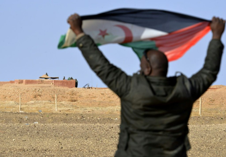 A Sahrawi, in February 2017, holds aloft a Polisario flag under the watchful eyes of Moroccan soldiers guarding an observation post on the 2,700-kilometre long wall (1,700 miles) that Rabat built to defend its control of the disputed Western Sahara