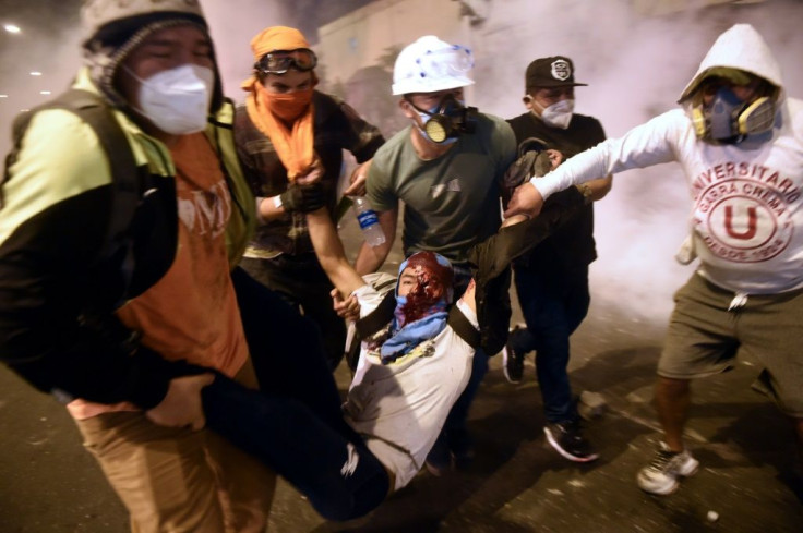 A demonstrator is helped by fellow protestors after being injured during clashes with riot police in Lima