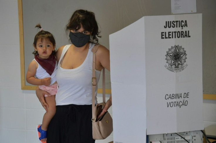 A woman carrying a child votes at a polling station in Sao Paulo during Brazil's municipal elections on November 15, 2020