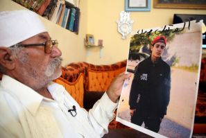 Libyan Mohamed al-Magri holds a picture of his 20-year-old missing son Haitham who he believes was killed and buried in a mass grave in the western city of Tarhuna after armed men took him from his home a year ago