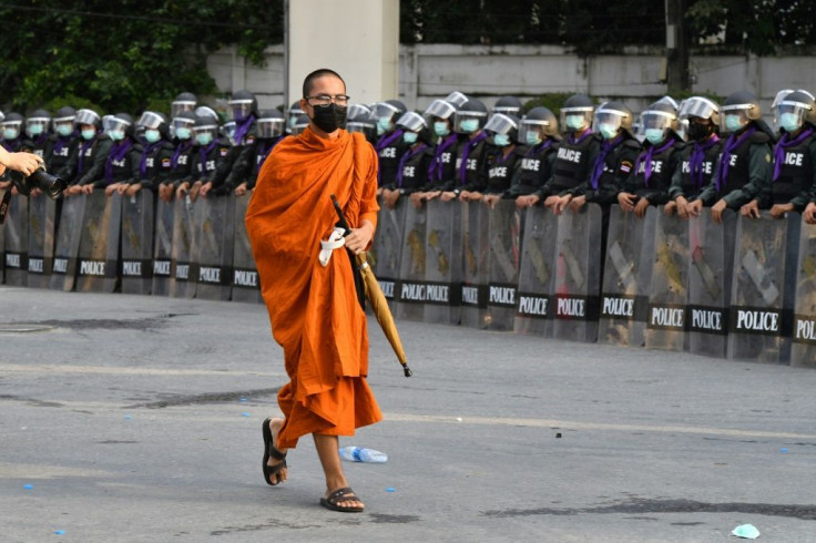 A Buddhist monk walks past riot police standing guard during an anti-government rally by pro-democracy protesters in Bangkok on November 17, 2020