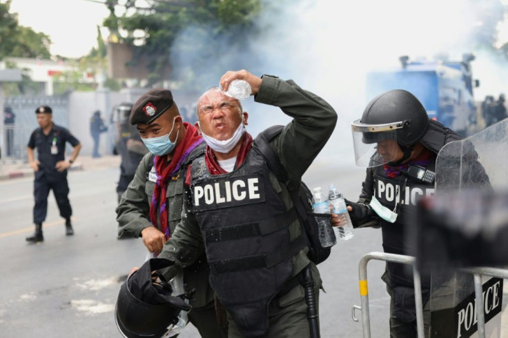 A policeman rinses tear gas from his eyes during the huge protest in Bangkok