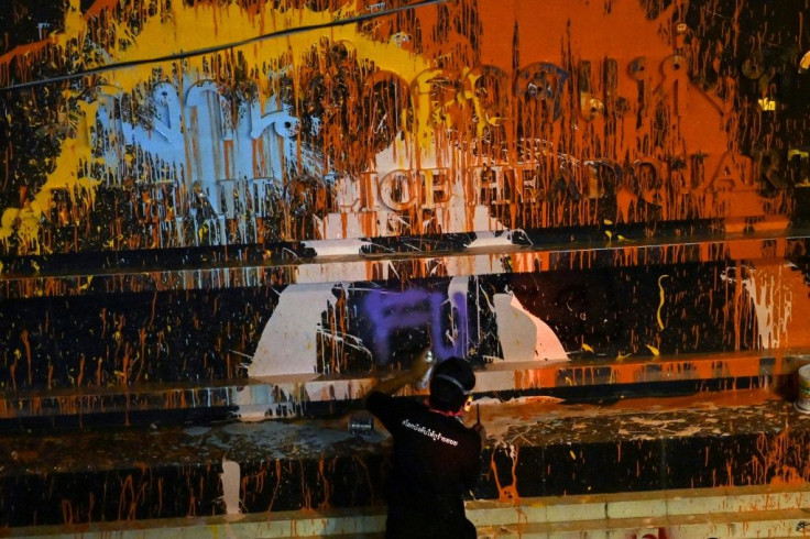 A protesters sprays a word on the paint-splashed sign of the Thai police headquarters in Bangkok