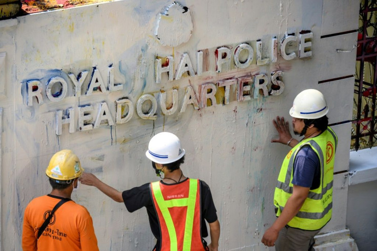 Workers clear up after protesters daubed graffiti on the walls of the Thai police headquarters