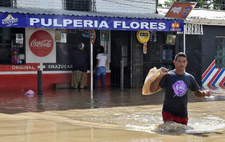 A man wades across a street as people buy products at a store in La Lima near San Pedro Sula in Honduras, on November 19, 2020