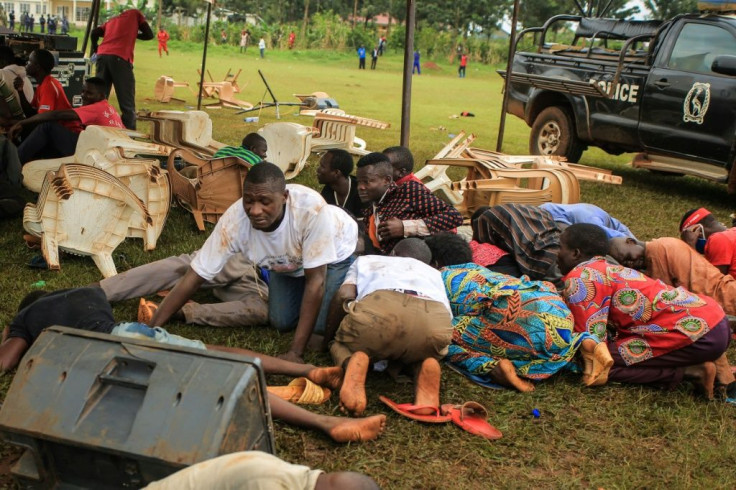 Wine supporters take cover from tear gas shot by police at the Kampala rally