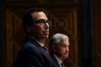Treasury Secretary Steven Mnuchin and Federal Reserve Chair Jerome Powell in background have disagreed on whether emergency lending programs should be extended