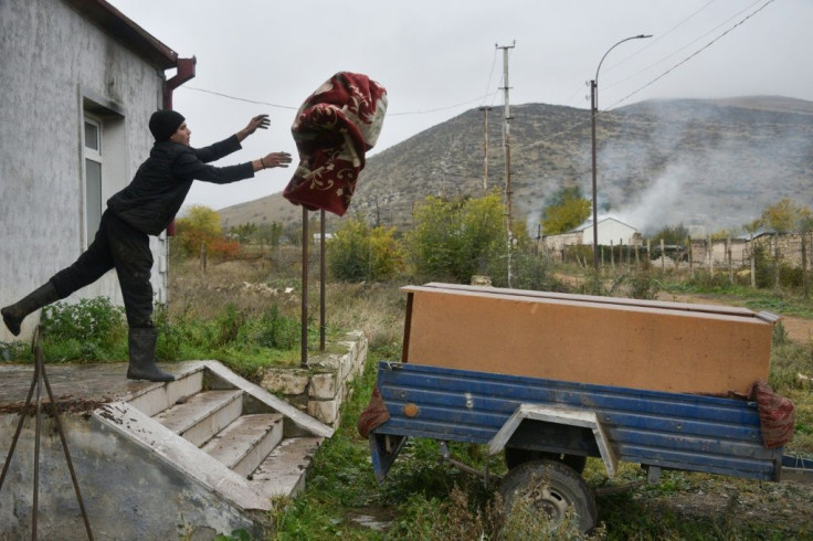 An Armenian man throws a carpet into a car trailer as he leaves the village of Nor-Karmiravan outside Agdam, before the territory was returned to Azerbaijan