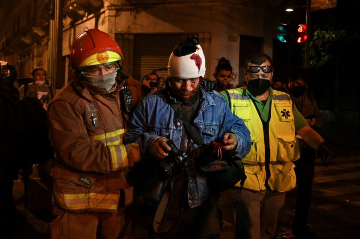 Municipal firefighters attend to photographer Carlos Sebastian who was injured during a protest demanding the resignation of Guatemalan President Alejandro Giammattei, in Guatemala City on November 21, 2020