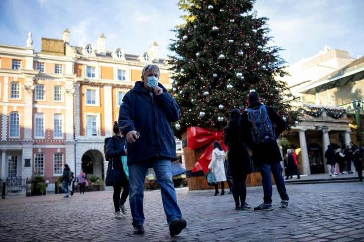 Pedestrians in face masks walk past a Christmas tree in London's Covent Garden