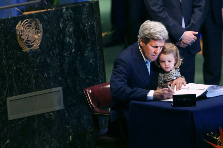 Former US secretary of state John Kerry signs the Paris climate accord at the UN building in New York, with his granddaughter Isabel Dobbs-Higginson seated on his knee
