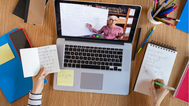 Person taking notes in front of Macbook