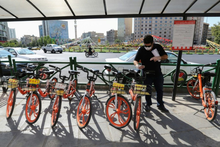 An Iranian man uses his phone to unlock a bicycle of bike-sharing service Bdood at Valiasr Square in Tehran