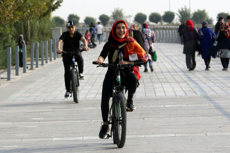 An Iranian woman rides a bicycle around the artificial Chitgar lake in Tehran, a city notorious for its traffic jams and smog