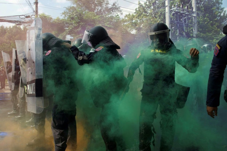 Green smoke engulfs a line of police near parliament in Bangkok