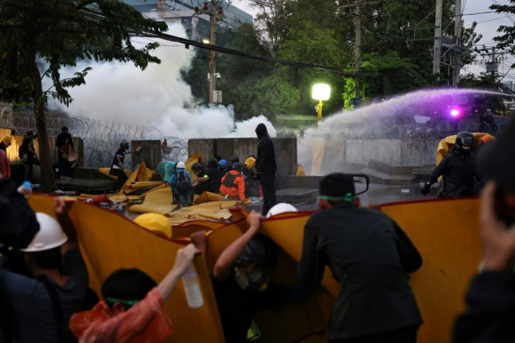 Pro-democracy protesters take shelter from police water cannons in Bangkok