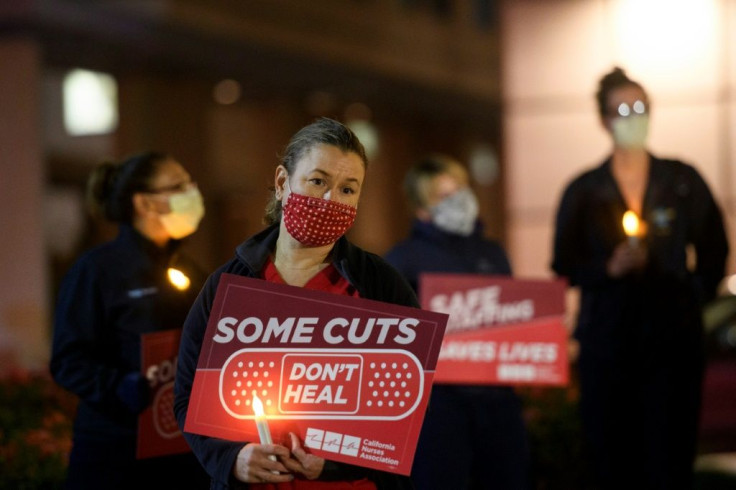 Nurses hold candles during a vigil for healthcare workers who died from Covid-19 organized by California Nurses United outside of UCLA Medical Center in Los Angeles