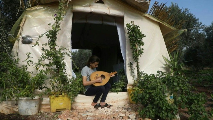 Among the olive trees in northwestern Syria, displaced teenager Wissam Diab plucks an oud outside his new home. Syria's war forced the Diab family to flee their village of Kafr Zita so 19-year-old Wissam decided to recreate his childhood home.