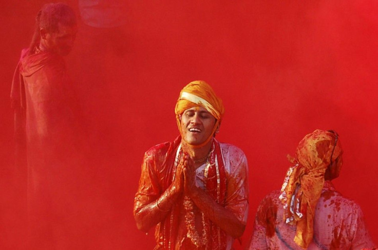 A man daubed in colours prays during Lathmar Holi celebrations at Nandgaon village