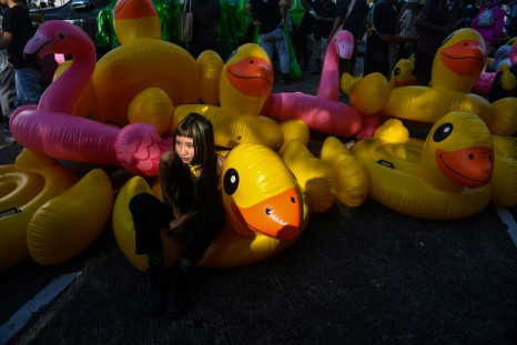 A Thai pro-democracy protester poses with inflatable yellow ducks that have become a symbol of the movement