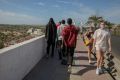 Malian migrants walk past a group of tourists in Gran Canaria, after being rescued by the Spanish coast guard