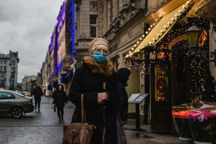 A woman wearing a face mask walks down a street in central Moscow on November 25, 2020, as cases continue to climb globally