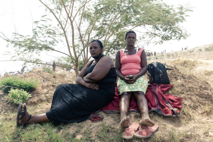 Relatives of trapped miners sit in the shade of a tree as they await an update from authorities