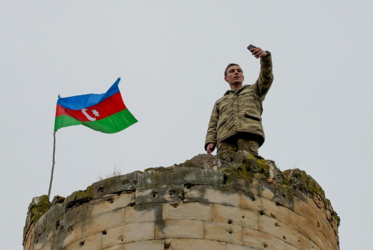 An Azerbaijan soldier takes a selfie with a national flag on the top a tower outside the town of Fuzuli