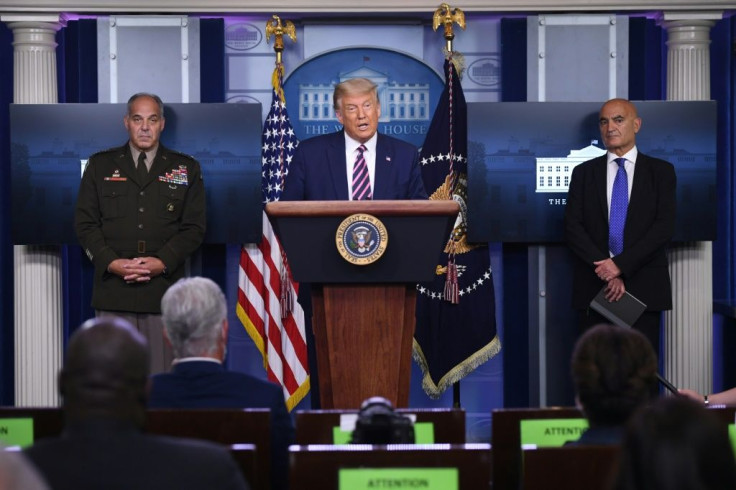 President Donald Trump, flanked (L) by General Gustave Perna, head of operations of Operation Warp Speed, and (R) Moncef Slaoui, the program's chief scientist, on September 18, 2020 at the White House