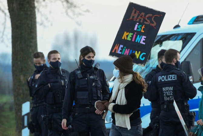 A woman with a placard reading 'hate is no opinion'  walks past police officers during an anti-AfD demonstration