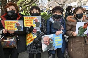 Protesters held pictures of an effigy of former South Korean President Chun Doo-hwan outside a court in Gwangju where his defamation trial took place