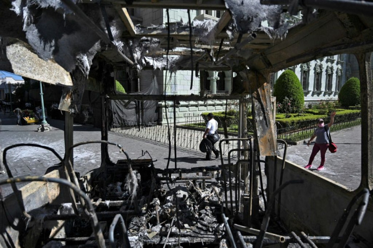 People are seen near a burnt bus a day after a protest to demand the resignation of Guatemalan President Alejandro Giammattei in Guatemala City on November 29, 2020
