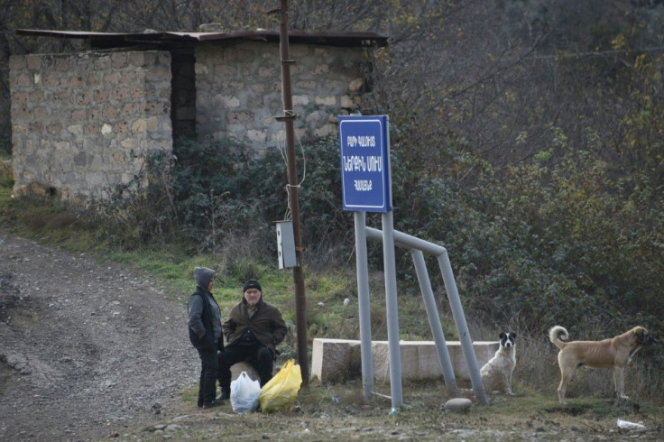 People with their belongings wait on the side of a road on the outskirts of the town of Lachin