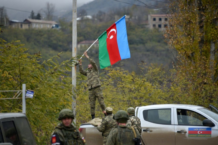 An Azerbaijani soldier fixes a national flag on a lamp post in the town of Lachin,  the final district given up by Armenia in a peace deal that ended weeks of fighting over disputed Nagorno-Karabakh
