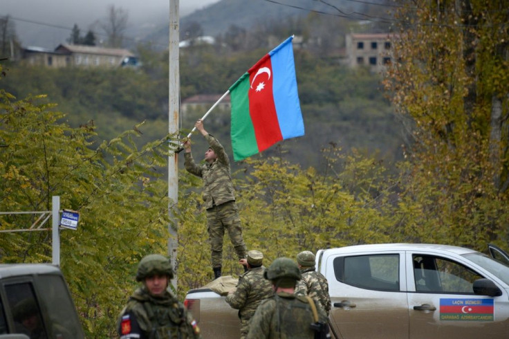 An Azerbaijani soldier fixes a national flag on a lamp post in the town of Lachin, the final district given up by Armenia in a peace deal that ended weeks of fighting over disputed Nagorno-Karabakh