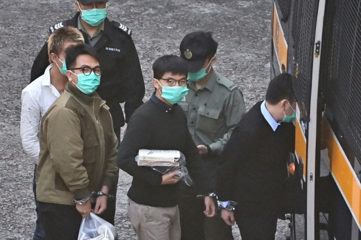 Hong Kong activists Joshua Wong (C) and Ivan Lam (L) board a police van before going to court to be sentenced over a protest last year