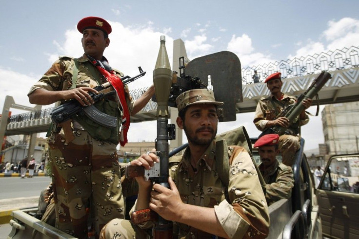 Army soldiers stand guard as anti-government protesters shout slogans at a barrier blocking a demonstration in Sanaa