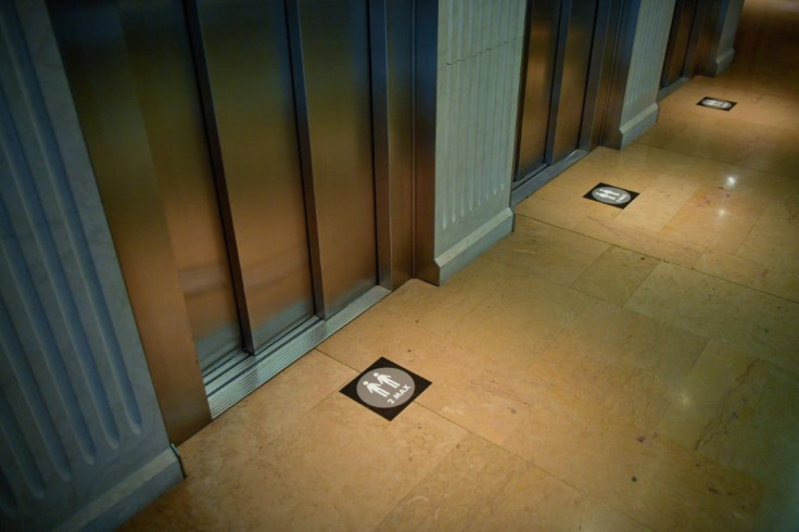 "Two people maximum" signs are pasted on the floor next to elevators at the Hotel Claris
