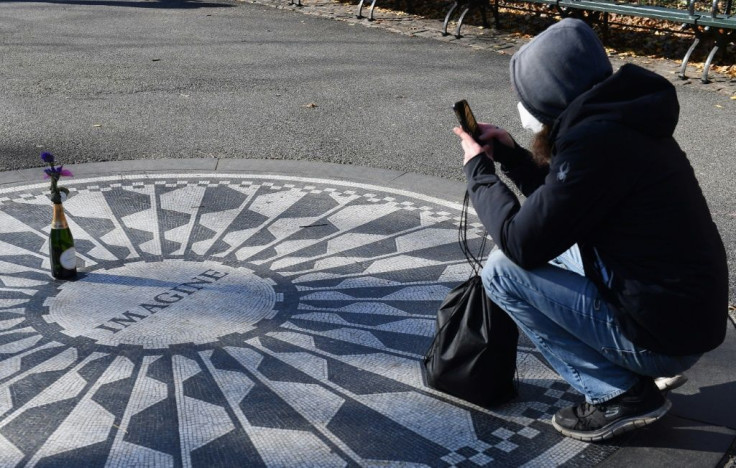 A fan takes a picture after placing a champagne bottle with flowers on the "Imagine" mosaic at the Strawberry Fields Memorial for John Lennon in Central Park, a few days before the 40th anniversary of his death on December 8