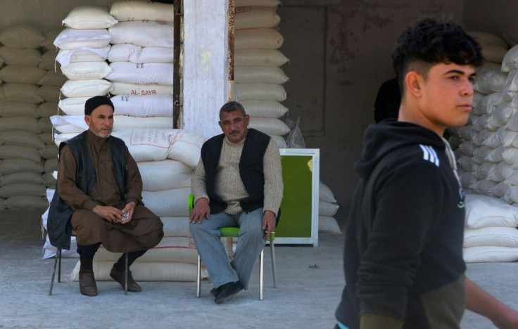 An Iraqi man (L) buys goods at a shop at the "Al-Bursa" wholesale market in the northern city of Mosul