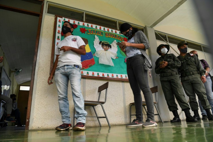 Voters queue keeping sanitary distancing measures at a polling station in a school in Caracas, on December 6, 2020 during Venezuela's legislative elections