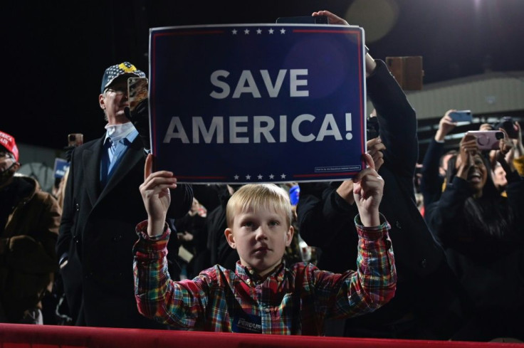 A boy holds a "Save America" sign as US President Donald Trump speaks at a tightly packed rally of thousands of mostly unmasked supporters in Valdosta, Georgia on December 5, 2020